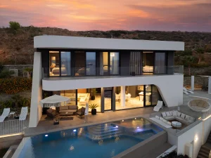 Modern Meltemi Villa exterior with illuminated infinity pool at sunset.