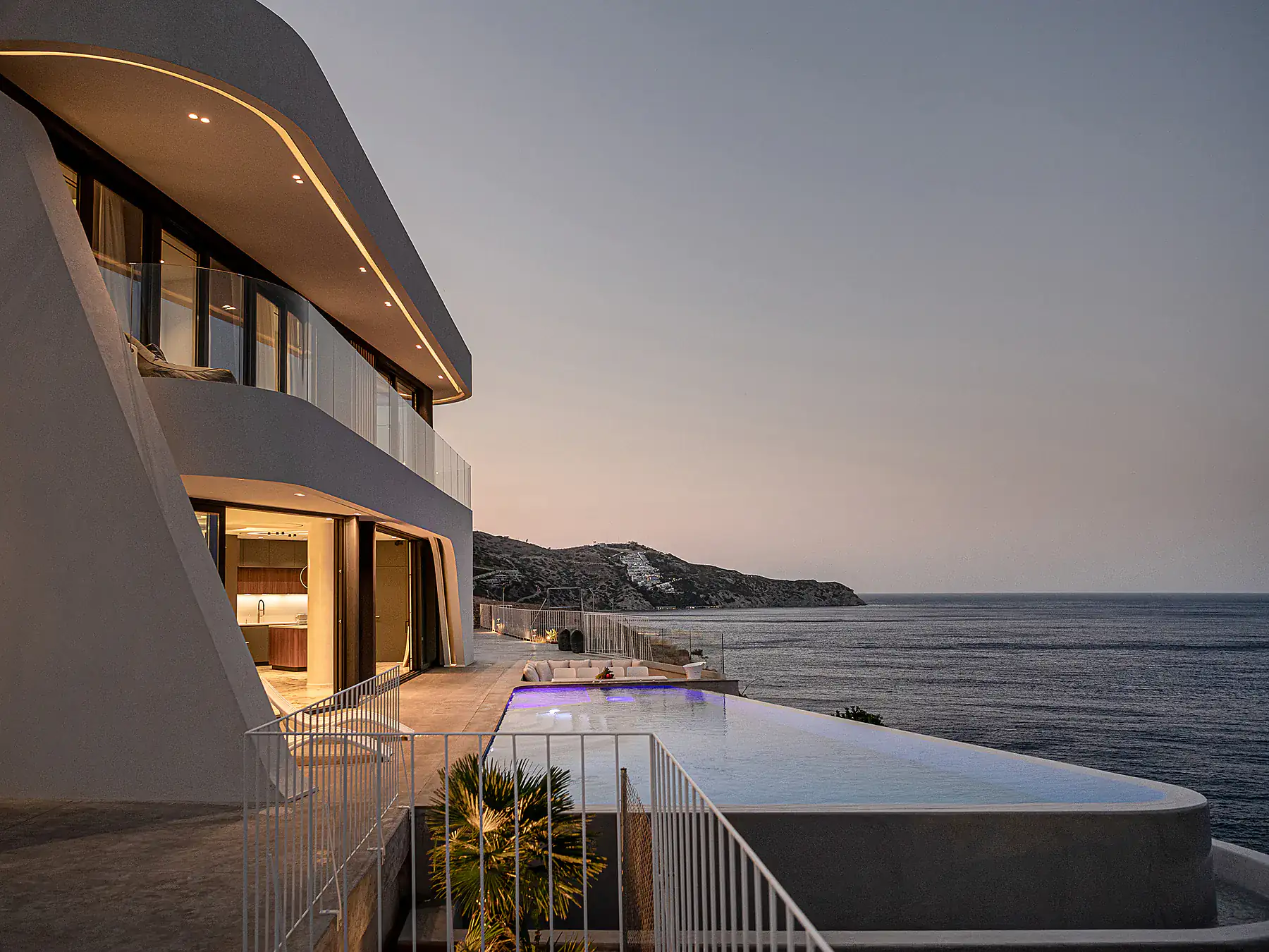 Sunset view of modern beachfront villa with seamless indoor-outdoor design.