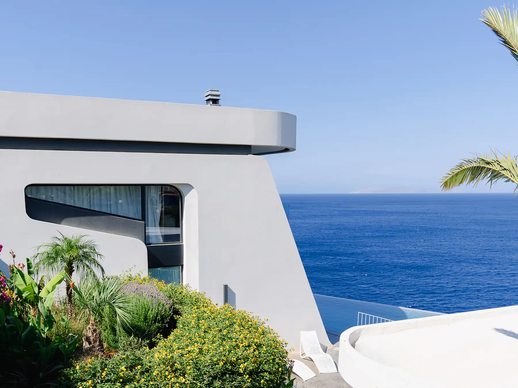 Modern villa terrace with ocean backdrop and architectural white facade.