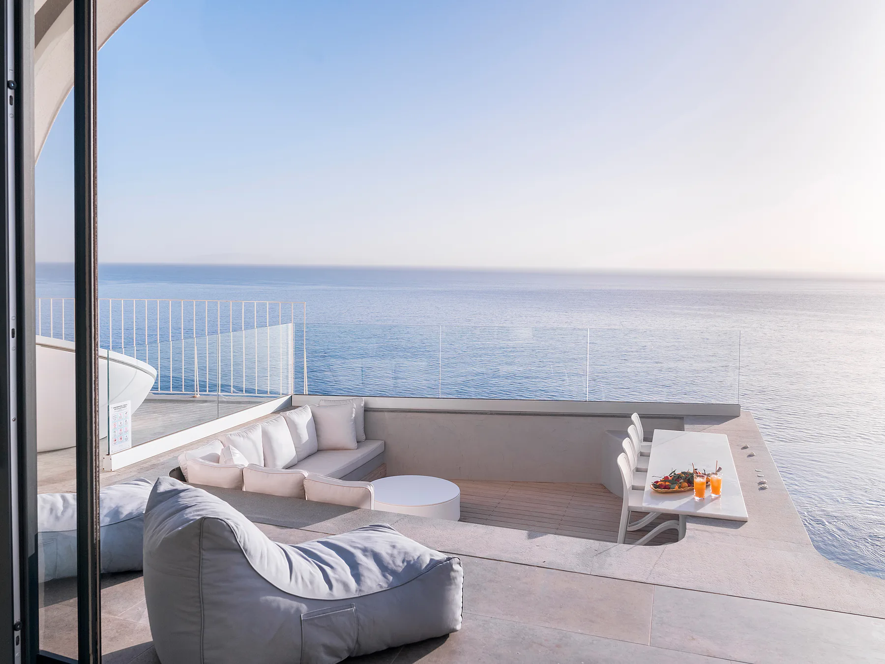 Oceanfront terrace lounge with soft seating and fire pit facing the Mediterranean.