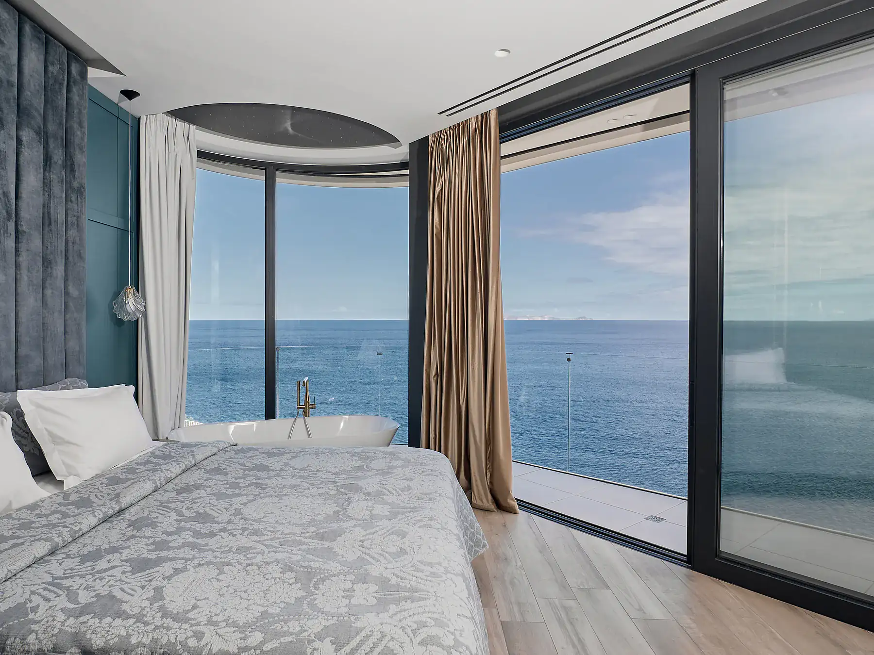 Luxury master bedroom with floor-to-ceiling windows and panoramic sea view.